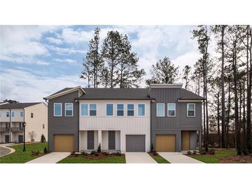 Modern townhome duplex featuring a two-car garage, neutral paint, and manicured lawn and landscaping at 1714 Gunnin Nw Trce # 237, Atlanta, GA 30318