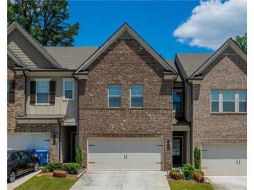 Charming brick townhome featuring a two-car garage and well-maintained landscaping at 221 Irwell Path, Lawrenceville, GA 30044