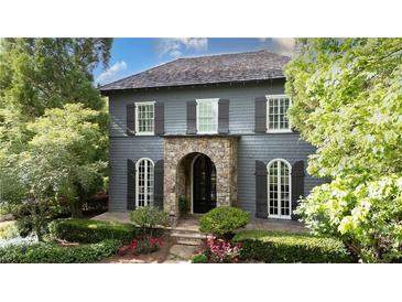 Charming two-story home featuring gray siding, black shutters, and a stone archway at the entrance at 6805 Bucks Rd, Cumming, GA 30040