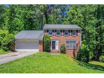 Charming two-story brick home featuring a well-maintained lawn, attached garage, and mature trees at 1076 Plantation Se Blvd, Conyers, GA 30094