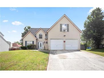Charming two-story home featuring a two-car garage and a well-maintained front lawn on a clear, sunny day at 7270 Williamsburg Dr, Riverdale, GA 30274