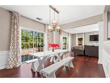 Bright dining area featuring hardwood floors, a white table with benches, and sliding glass doors to the backyard at 5010 Foxberry Ln, Roswell, GA 30075