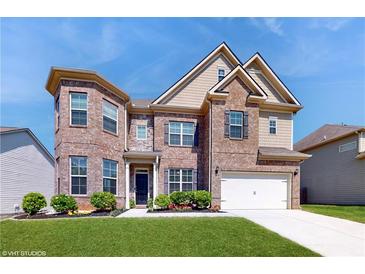 Charming two-story brick home featuring manicured landscaping, a two-car garage, and a welcoming front entrance at 205 Kestrel Cir, Covington, GA 30014