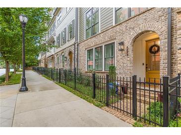 Charming townhomes with brick facade, arched entryways, and black wrought iron fences along a tree-lined street at 976 Memorial Se Walk, Atlanta, GA 30316