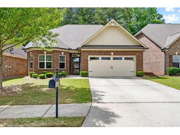 Charming brick home with a two-car garage, a well-manicured lawn and mature landscaping at 2212 Nichols Valley Drive, Dacula, GA 30019