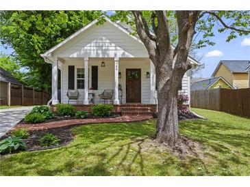 Charming home featuring a landscaped yard and welcoming front porch with brick steps and seating area at 94 Glenn Se St, Atlanta, GA 30312