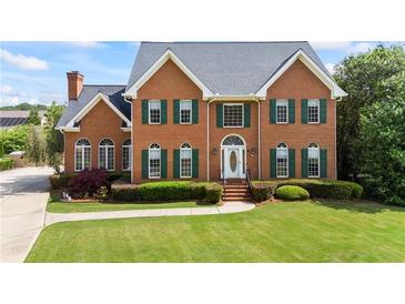 Charming brick home featuring a manicured lawn, green shutters, and a welcoming front entrance at 1402 Bromley Dr, Snellville, GA 30078