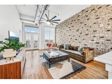 Inviting living room showcasing exposed brick wall, hardwood floors, and stylish modern furniture at 3820 Roswell Ne Rd # 705, Atlanta, GA 30342