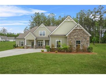 Charming single-story home featuring a mix of stone and green siding, complemented by a lush green lawn at 100 Nemoura Ct, Fairburn, GA 30213