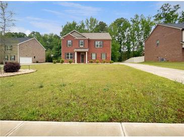 Charming two-story brick home with a lush green lawn and beautiful landscaping in a quiet, residential neighborhood at 1477 Harlequin Way, Stockbridge, GA 30281