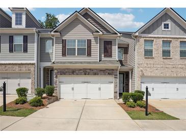 Charming townhome featuring a two-car garage and professionally landscaped front yard at 5527 Fairhaven Pl, Fairburn, GA 30213