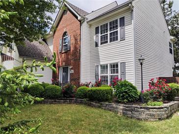 Charming two-story home with brick and white siding, complemented by a well-maintained lawn and colorful flower beds at 3060 Baymount Dr, Lawrenceville, GA 30043