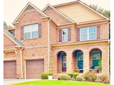 Charming brick home featuring arched entryway, manicured lawn, and two-car garage at 1185 Gallatin Way, Suwanee, GA 30024