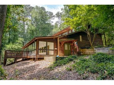 Inviting log home with a deck and lush landscaping creates a private and serene setting at 605 Ga 120 Hwy, Roswell, GA 30075