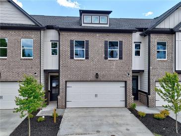 Charming townhome exterior featuring a brick facade, attached garage, and well-manicured landscaping at 5702 Urban Village Way # 2, Tucker, GA 30084