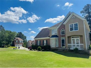 Charming two-story home with a well-manicured lawn, brick accents, and lush landscaping on a sunny day at 479 Rising Sun Path, Lawrenceville, GA 30043
