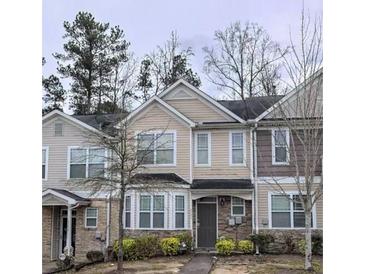 Traditional townhouse exterior featuring beige siding, multi-pane windows, and well-maintained landscaping at 2366 Bigwood Trl, Atlanta, GA 30349