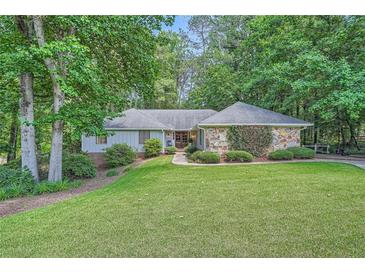 Charming single-story home featuring a well-manicured lawn and a stone facade, surrounded by mature trees at 125 Fortuna Ct, Roswell, GA 30075