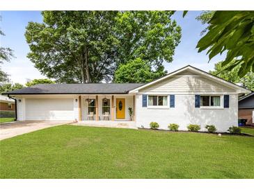 Charming one-story home with a well-manicured lawn, bright yellow door, and an attached two car garage at 3890 Cherrydale Se Ln, Smyrna, GA 30082