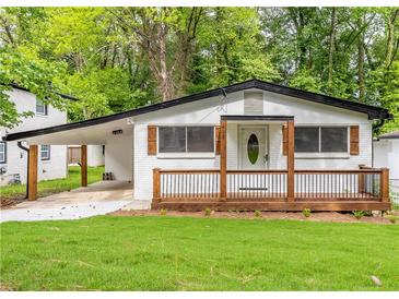 Charming home features a welcoming front porch and freshly painted white brick exterior at 493 Woods Nw Dr, Atlanta, GA 30318