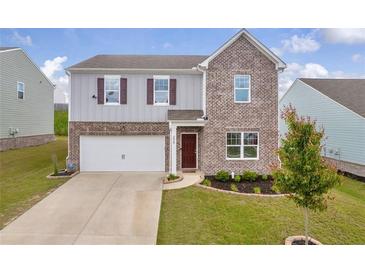 Two story home featuring a brick and gray facade, attached garage, and a well manicured lawn at 3828 Ramsay Pass, Loganville, GA 30052