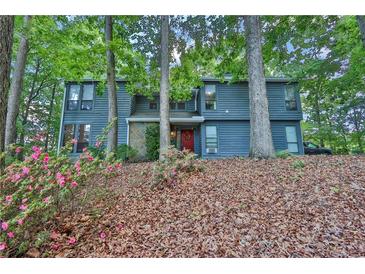 Inviting two-story home with beautiful landscaping and a charming red front door nestled among mature trees at 3067 Nuptial Ln, Lawrenceville, GA 30044