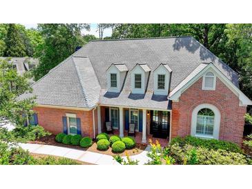 Charming brick home with a covered porch, manicured landscaping, and a well-maintained lawn at 1830 Hadfield Blvd, Roswell, GA 30075