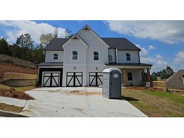 Striking new construction home showcasing white vertical siding and three-car black and white garage doors at 222 Silvercrest Dr, Acworth, GA 30101