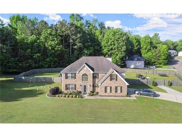 Charming two-story brick home with a well-manicured lawn and mature trees at 423 Blackbird Way, Hampton, GA 30228