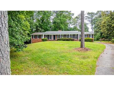 A sprawling front yard leads up to a brick home with a long, covered front porch at 3916 Ridgewood Se Dr, Smyrna, GA 30080
