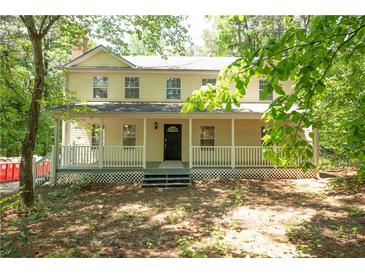 Two-story home with a welcoming front porch, black front door, and surrounded by mature trees in a serene setting at 535 Toonigh Rd, Woodstock, GA 30188