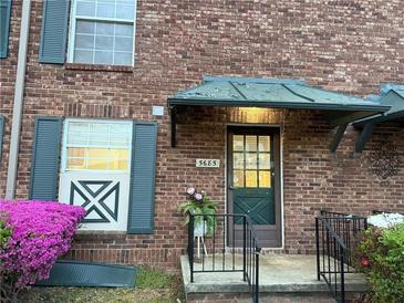 Charming brick home featuring an inviting entrance with green door and lush flowering plants at 5685 Kingsport Dr, Sandy Springs, GA 30342