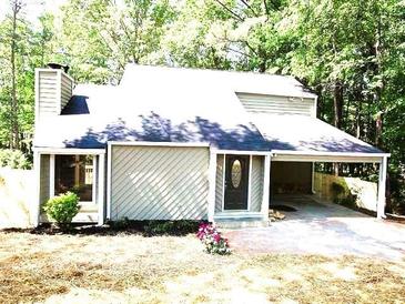 Charming one-story home with siding, chimney and attached carport in wooded setting at 215 Carmichael Rd, Woodstock, GA 30189