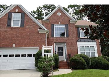 Charming red brick two-story home with manicured lawn and attached two car garage at 442 John Stewart Pl, Suwanee, GA 30024