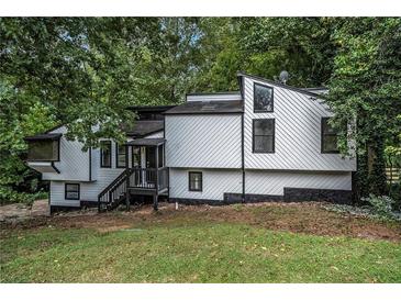 Contemporary home featuring modern design, white siding, black trim, nestled within a lush, wooded landscape at 336 Rockmoor Trl, Marietta, GA 30066