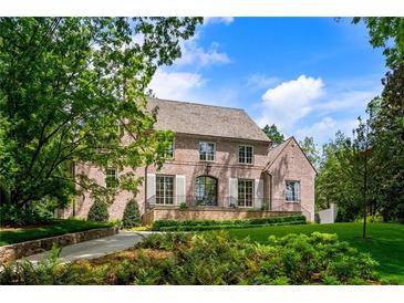 Elegant brick home featuring manicured landscaping, a lush lawn, and mature trees on a sunny day at 2515 Habersham Rd, Atlanta, GA 30305