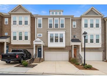 Beautiful townhome with brick and siding, a covered front porch, and an attached garage at 1098 Caruso Dr, Buford, GA 30518