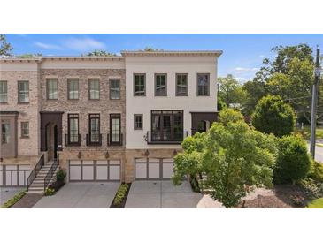Charming townhome showcasing a brick facade, a covered front porch, and a two-car garage at 210 Marjean Way, Alpharetta, GA 30009