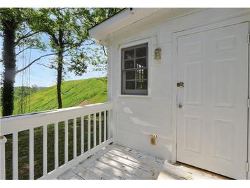 Side view of white house with a white railing and a door, against the backdrop of a grassy hill at 4682 Stonewall Tell Rd, College Park, GA 30349