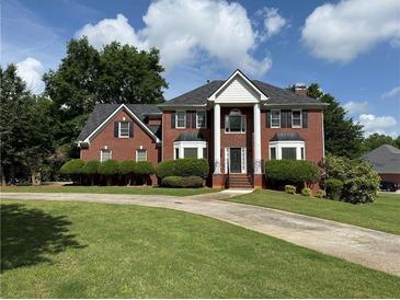 Traditional red brick home with large columns and a well-manicured front lawn under a bright sky at 1301 Winesap Se Ct, Conyers, GA 30013