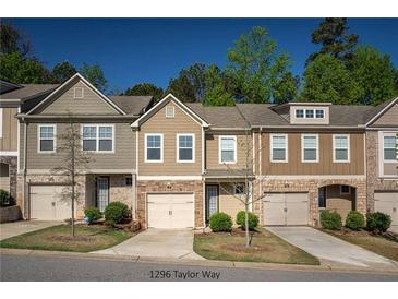 Charming townhomes showcasing varied color palettes, brick accents, and single-car garages under a clear blue sky at 1296 Taylor Way, Stone Mountain, GA 30083
