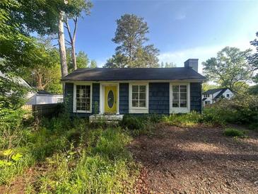 Cottage-style home featuring a yellow door and blue siding amidst lush greenery in a wooded setting at 1417 Richland Rd, Atlanta, GA 30310