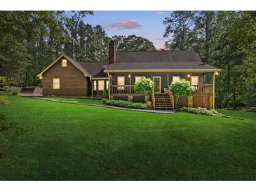 Inviting home featuring a well-manicured lawn and covered front porch nestled in mature trees at 4615 Gresham Rd, Douglasville, GA 30134