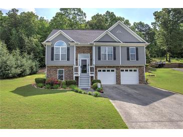 Charming two-story home featuring a stone facade, gray siding, manicured lawn, and a two-car garage at 20 Spruce Ne St, White, GA 30184