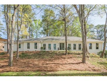 Inviting one-story home featuring a light brick facade, complemented by mature trees, and an open yard at 2729 Ridge Valley Nw Rd, Atlanta, GA 30327