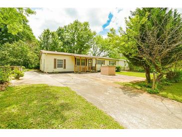 Inviting single-story home with charming front porch and mature trees around the property at 1303 Cochise Cir, Austell, GA 30168