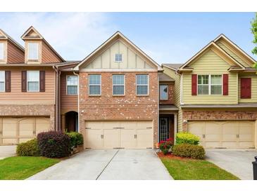 Charming brick townhome featuring a two-car garage and manicured front lawn at 1539 Creek Bend Ln, Lawrenceville, GA 30043