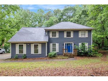 Charming two-story home with blue siding, white trim, bright blue front door, and mature trees at 295 N Fayette Dr, Fayetteville, GA 30214