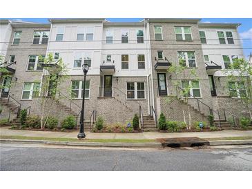 Beautiful three-story townhomes with brick and siding, landscaped with trees and greenery at 2505 Astaire Nw Ct, Atlanta, GA 30318
