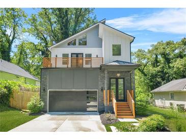 Modern two-story home with gray accent wall, balcony, sleek garage door, and professional landscaping at 2186 Park Terrace, College Park, GA 30337